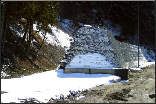 Photograph of a passive gabion rock barrier on a European Alpine mountain road.
